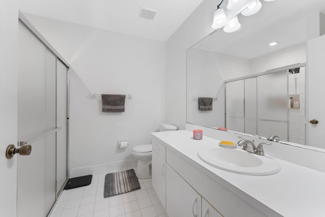 bathroom featuring toilet, vanity, tile patterned floors, and a shower with door