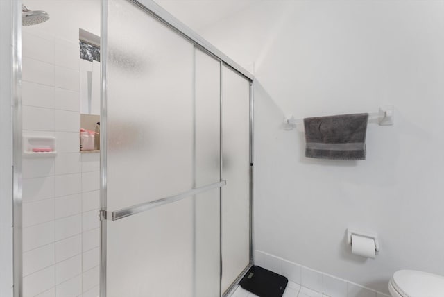 bathroom with tile patterned flooring, toilet, and an enclosed shower