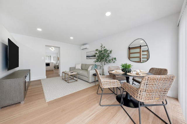 living room with a wall mounted air conditioner and light hardwood / wood-style floors