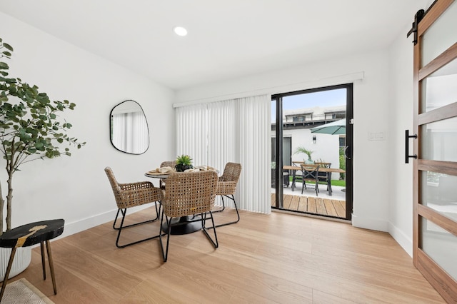 dining space with a barn door and light hardwood / wood-style floors