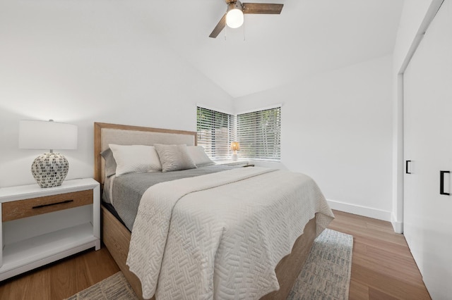 bedroom featuring ceiling fan, vaulted ceiling, a closet, and light hardwood / wood-style flooring