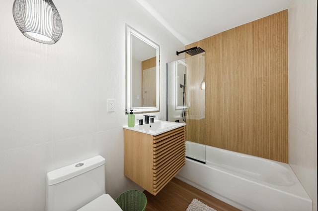 full bathroom featuring vanity, bathtub / shower combination, toilet, tile walls, and wood-type flooring