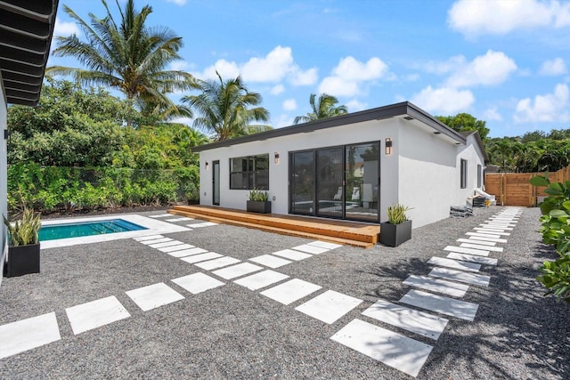 back of property with a pool side deck and a patio