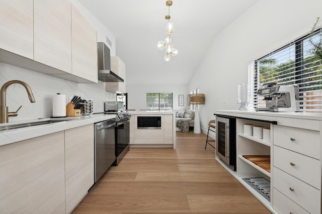 kitchen with stainless steel dishwasher, wall chimney exhaust hood, sink, light hardwood / wood-style flooring, and hanging light fixtures