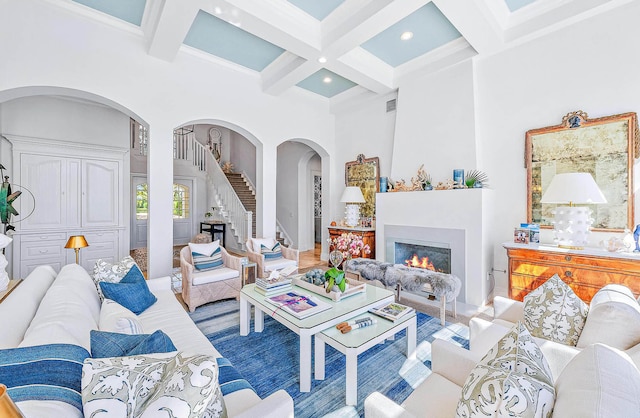 living room featuring a towering ceiling, beamed ceiling, and coffered ceiling