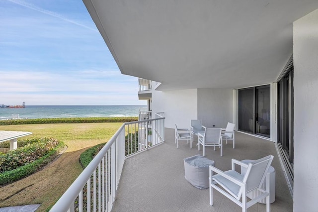 balcony with a water view and a view of the beach