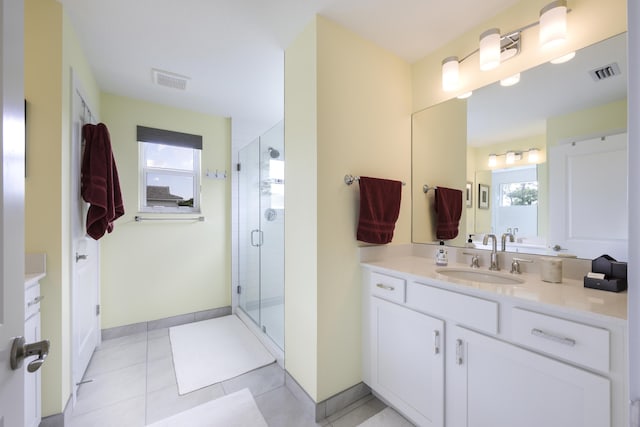 bathroom with tile patterned flooring, vanity, a healthy amount of sunlight, and a shower with door