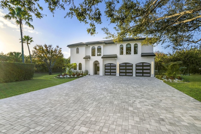 mediterranean / spanish house with a garage and a lawn