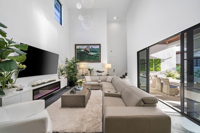 living room featuring a wealth of natural light, a high ceiling, and a notable chandelier