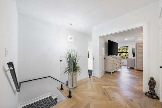 hallway with parquet floors and a notable chandelier