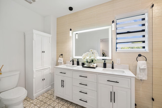 bathroom with tile patterned flooring, vanity, tile walls, and toilet