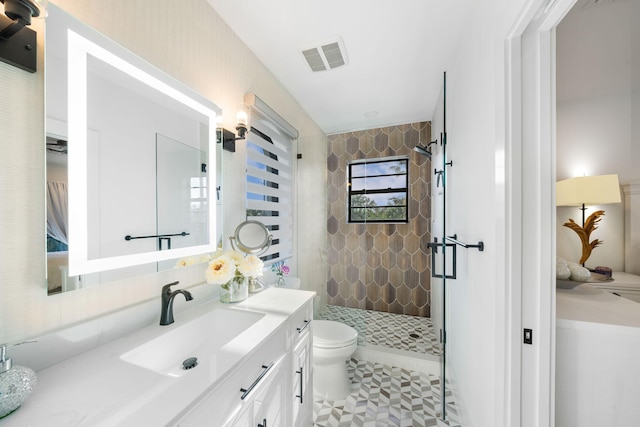 bathroom featuring a tile shower, tile patterned floors, vanity, and toilet