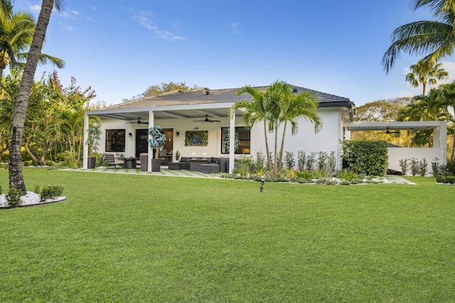 back of house with an outdoor living space, ceiling fan, a patio area, and a yard