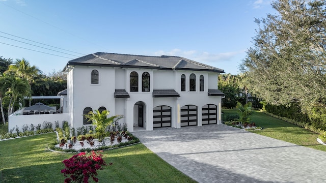 mediterranean / spanish home with a garage and a front lawn