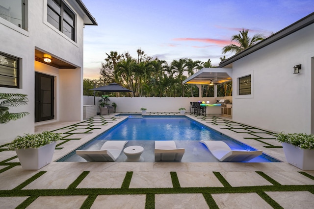 pool at dusk with a patio area