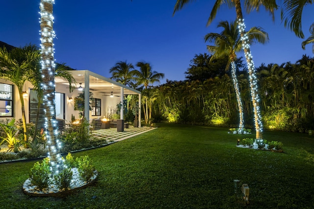 yard at twilight featuring a patio and ceiling fan