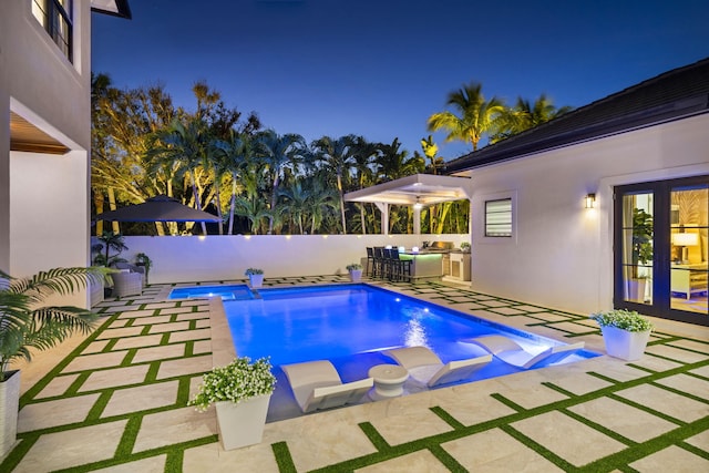 view of pool with french doors, a patio, and exterior kitchen