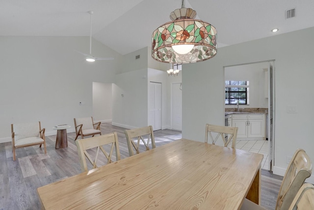 dining area with light hardwood / wood-style flooring, vaulted ceiling, ceiling fan, and sink