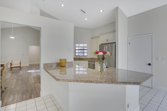 kitchen with sink, stainless steel appliances, light stone counters, kitchen peninsula, and light tile patterned floors