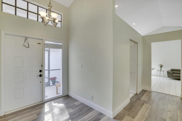 entryway featuring a notable chandelier, light wood-type flooring, and vaulted ceiling