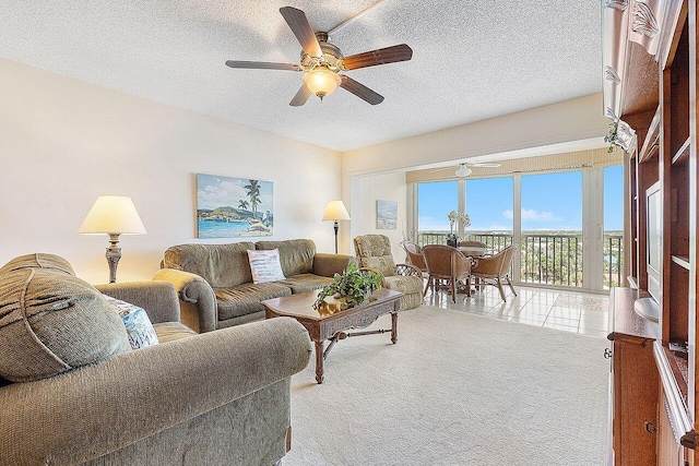 living area with a ceiling fan and a textured ceiling