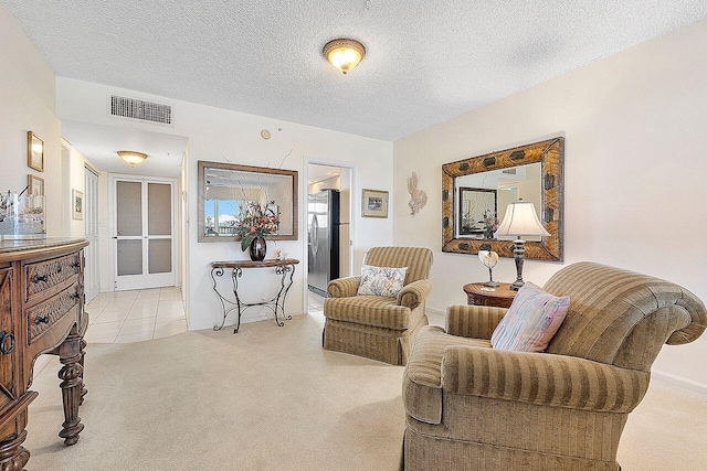 living area with carpet floors, a textured ceiling, and visible vents