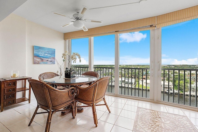 sunroom / solarium featuring a wealth of natural light, ceiling fan, and a water view