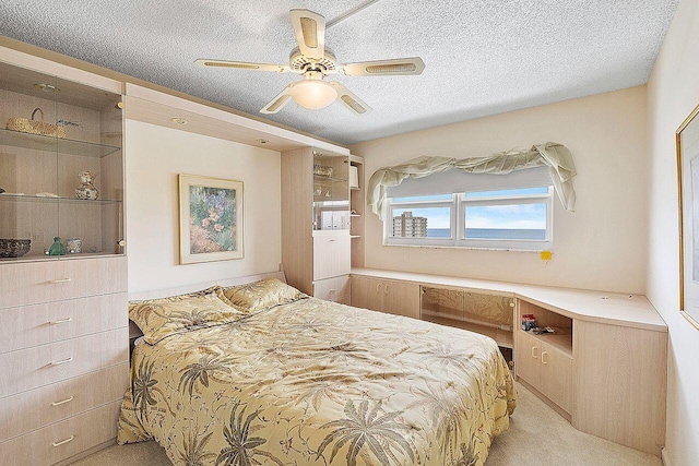 carpeted bedroom featuring ceiling fan and a textured ceiling