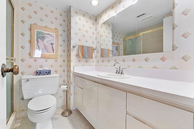 bathroom featuring toilet, vanity, tile patterned floors, and a shower with shower door