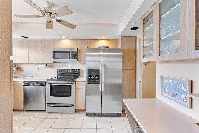 kitchen featuring light tile patterned flooring, light brown cabinetry, ornamental molding, ceiling fan, and stainless steel appliances