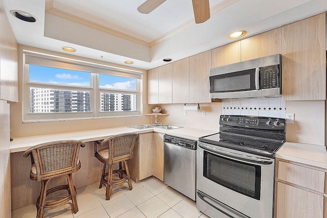 kitchen featuring light brown cabinetry, sink, light tile patterned floors, ornamental molding, and appliances with stainless steel finishes