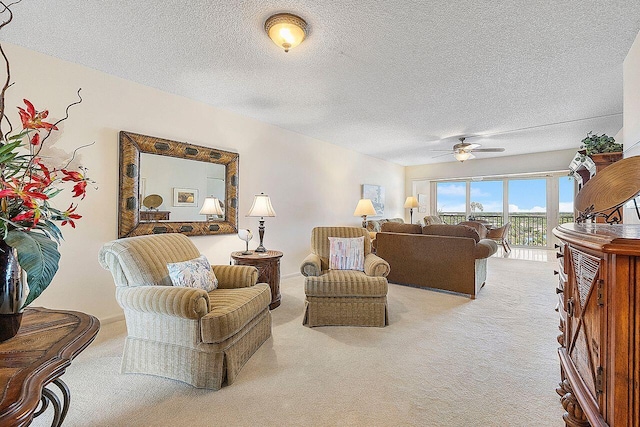 living room with ceiling fan, light colored carpet, and a textured ceiling