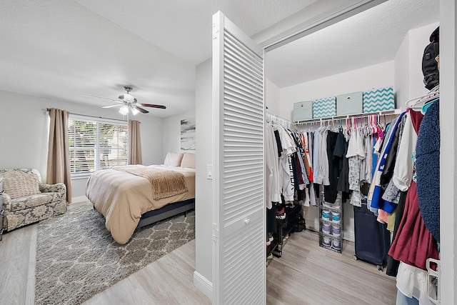 bedroom featuring ceiling fan, a textured ceiling, light wood-type flooring, and a closet