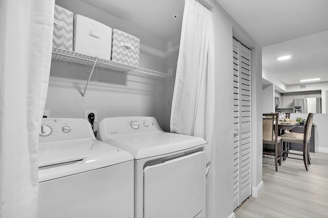 clothes washing area featuring washing machine and dryer and light hardwood / wood-style flooring