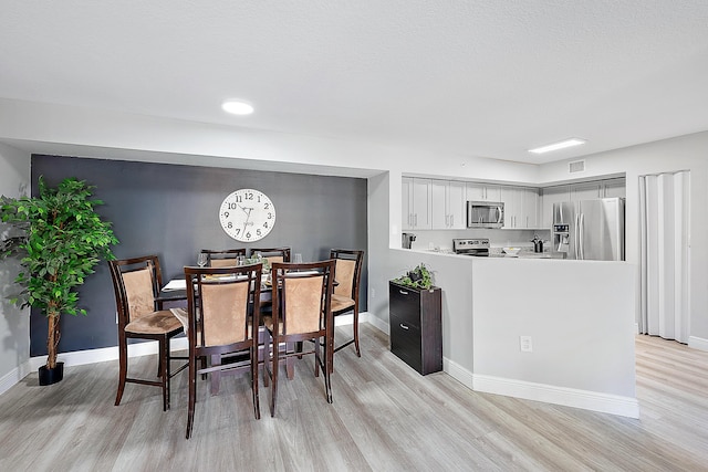 dining room with light hardwood / wood-style flooring and a textured ceiling