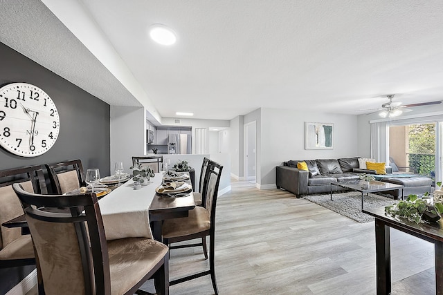 dining area featuring ceiling fan, light hardwood / wood-style flooring, and a textured ceiling