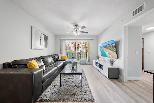 living room with ceiling fan, light hardwood / wood-style floors, and a textured ceiling