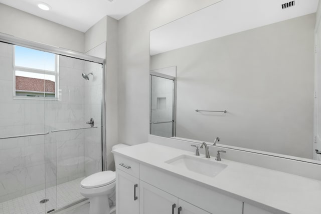 bathroom featuring vanity, toilet, and a shower with shower door