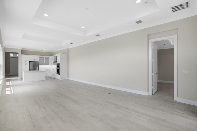 unfurnished living room with a raised ceiling and light hardwood / wood-style flooring