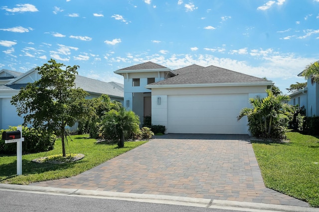 view of front facade with an attached garage, a shingled roof, decorative driveway, stucco siding, and a front yard