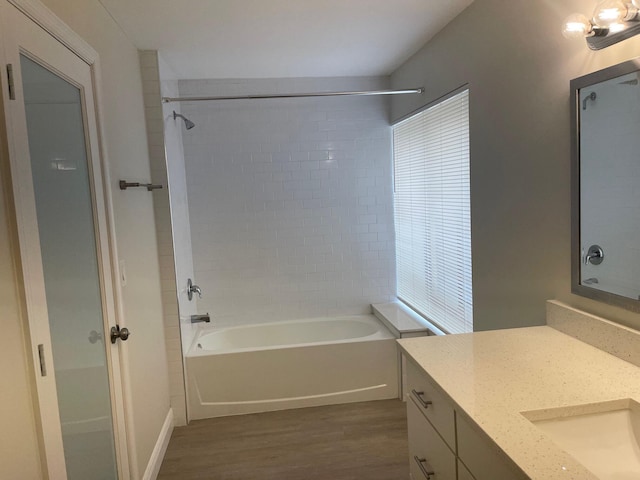 bathroom with vanity, hardwood / wood-style flooring, and tiled shower / bath