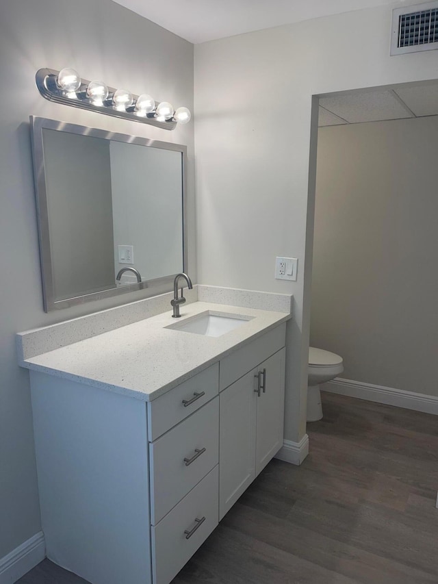 bathroom with wood-type flooring, vanity, and toilet