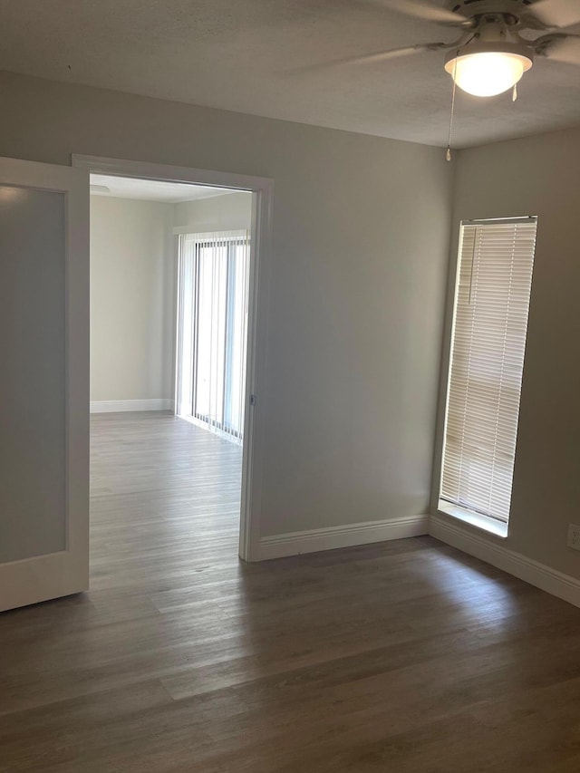 unfurnished room with ceiling fan and dark wood-type flooring