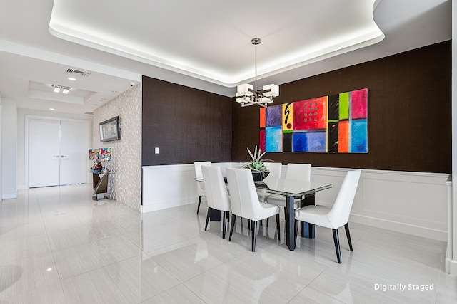 dining room featuring a chandelier, light tile patterned floors, and a raised ceiling