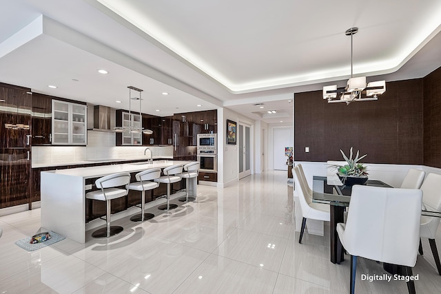 kitchen featuring dark brown cabinets, a kitchen island with sink, hanging light fixtures, and appliances with stainless steel finishes