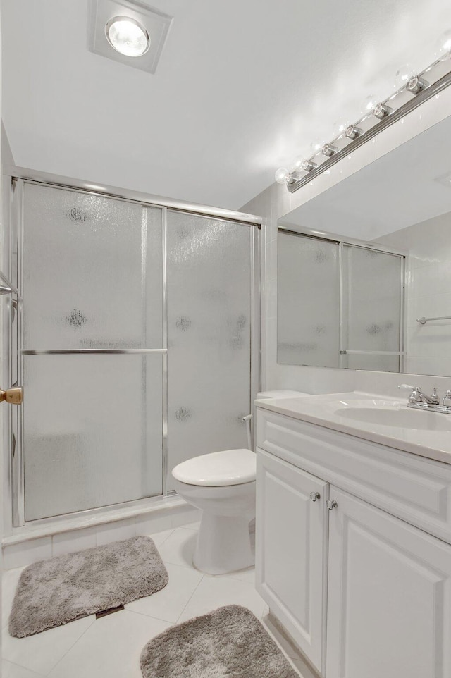 bathroom with tile patterned flooring, vanity, toilet, and a shower with shower door