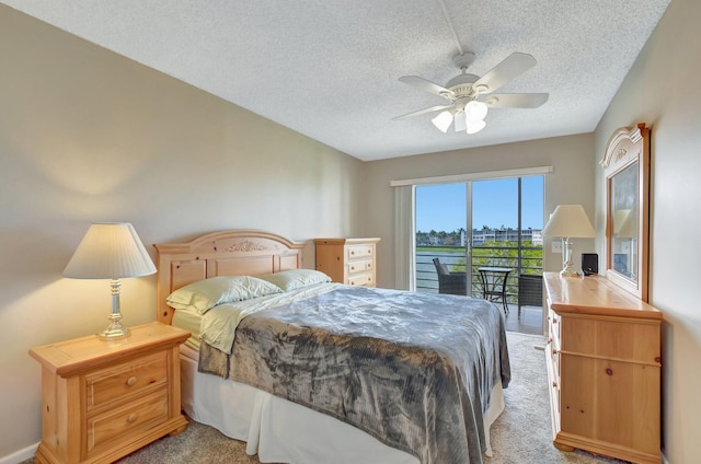 carpeted bedroom featuring access to outside, ceiling fan, and a textured ceiling