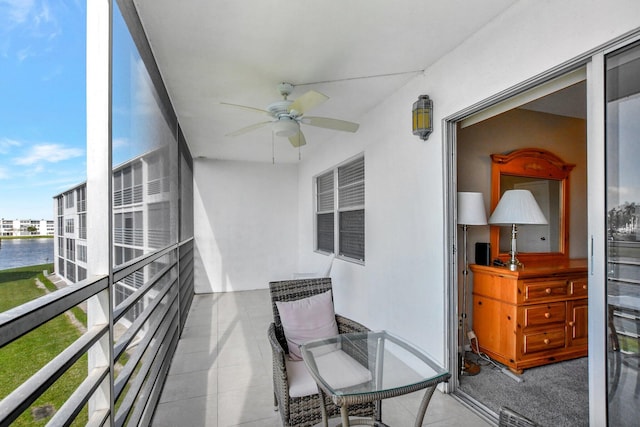 balcony with ceiling fan and a water view