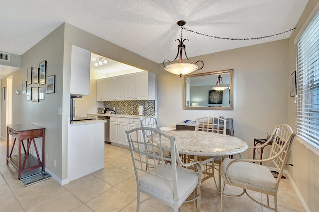 tiled dining room featuring plenty of natural light and a textured ceiling