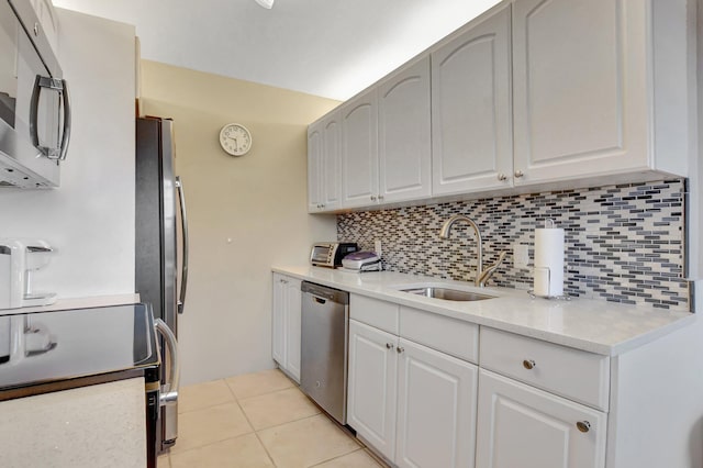 kitchen with white cabinetry, sink, stainless steel appliances, decorative backsplash, and light tile patterned floors